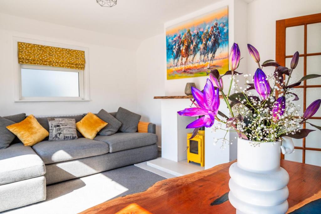 a living room with a couch and a vase with flowers at Beach Retreat Cottage- huge Garden Child & Dog friendly in Broadstairs