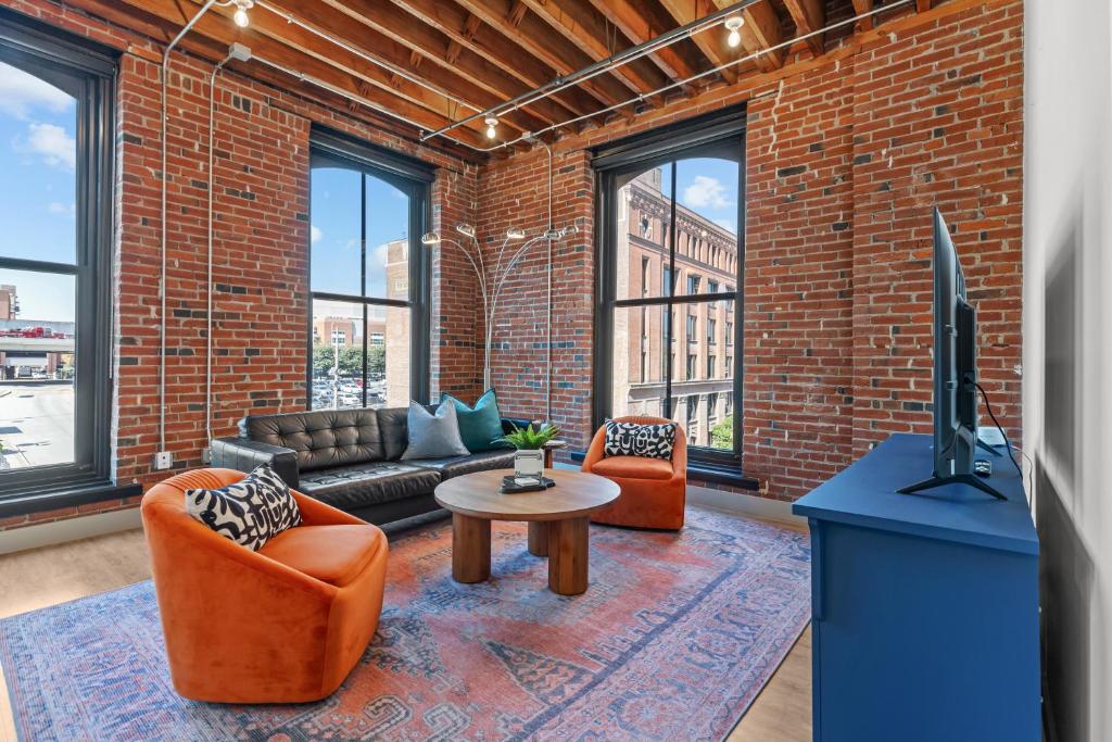 Una sala de estar con un sofá y sillas y un televisor. en Sunny & Spacious Loft - Perfect for Work and Play!, en Saint Louis