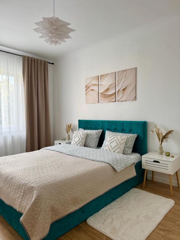 a bedroom with a large bed with a blue headboard at Emerald - Modern Central Apartment in Tîrnăveni