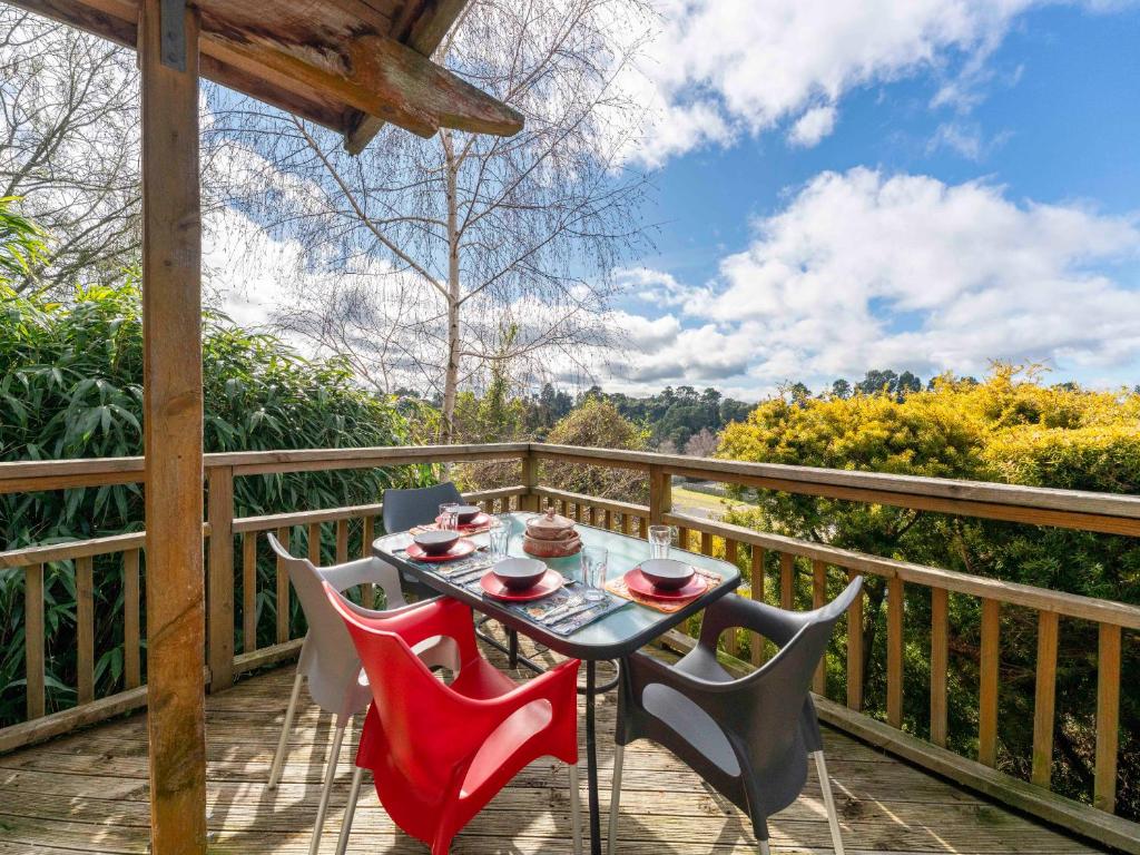 a table and chairs on a deck with a view at Treetop Hideaway - Taupo Holiday Home in Taupo