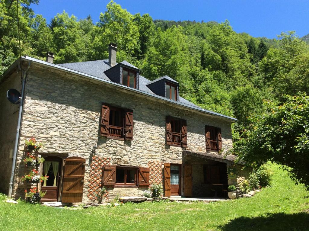 an old stone house with wooden balconies and trees at Les 3 Ours in Couflens