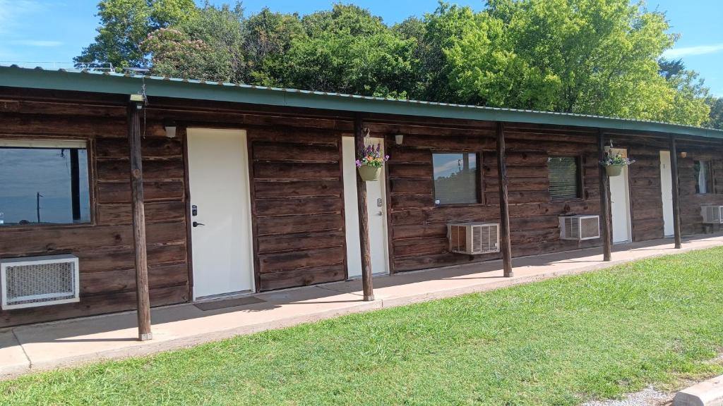 a wooden cabin with windows and a grass field at Hotel room #5 in Madill