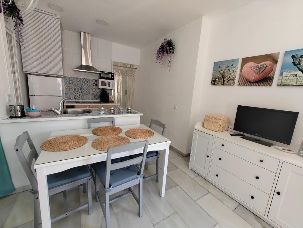 a kitchen with a table and chairs and a tv at Apartamento Pepote in Málaga