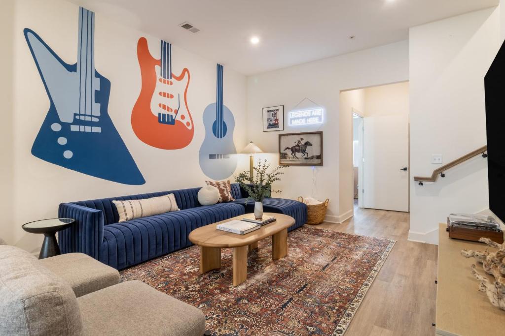 a living room with a blue couch and guitars on the wall at The Conway by AvantStay Modern Comfort Near Downtown Nashville in Nashville