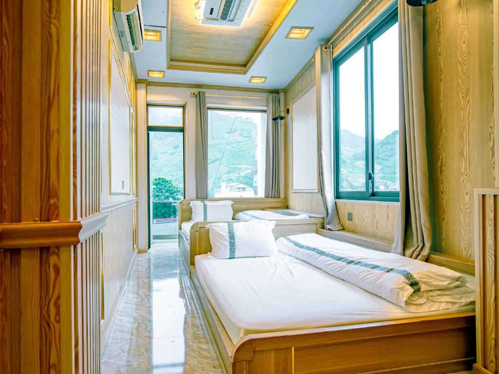 two beds sitting in a room with windows at Quyenly Motel Mèo Vạc in Mèo Vạc
