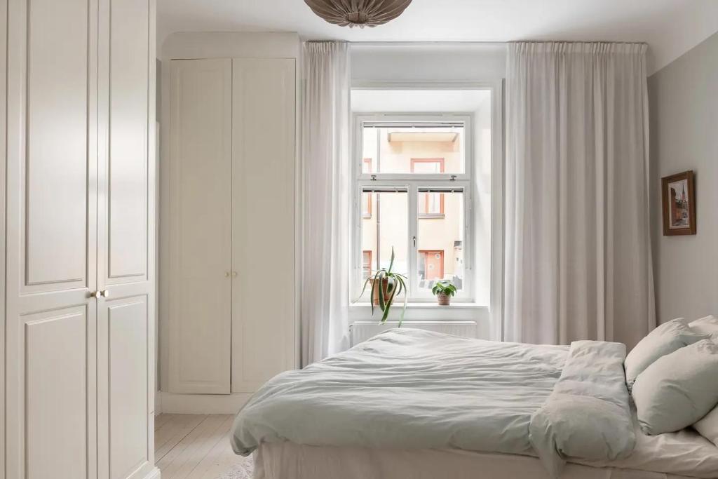 a white bedroom with a bed and a window at Modern och ljus lägenhet 