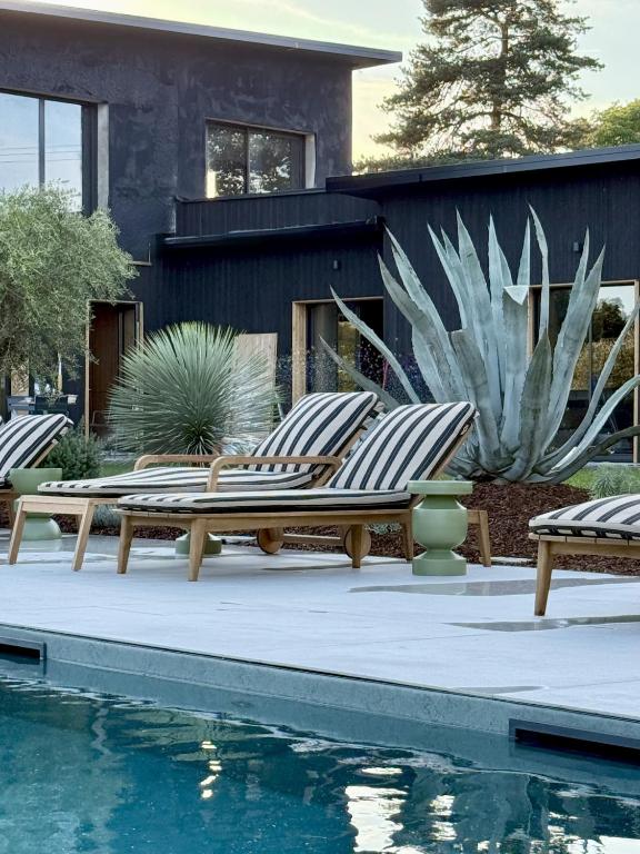 a group of lounge chairs next to a swimming pool at 537 Saint Emilion - Luxury Guest House in Saint-Laurent-des-Combes