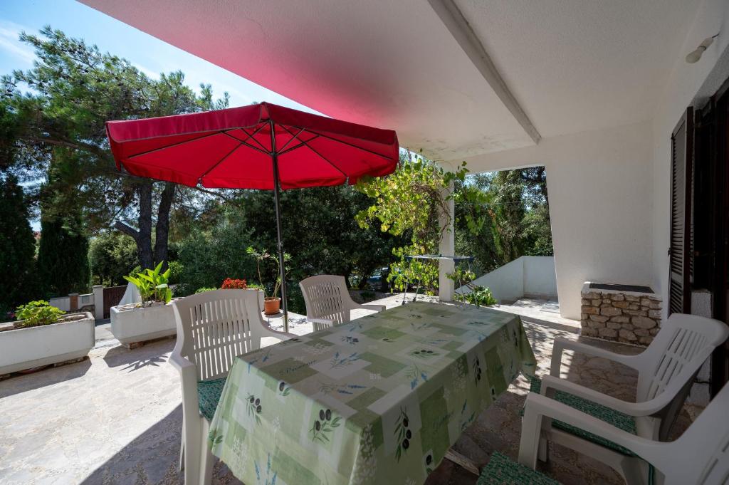 a table and chairs with a red umbrella on a patio at Apartments with parking space Mandre, Pag - 9420 in Kolan