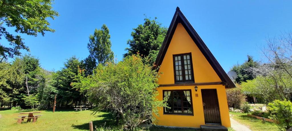 a small yellow house with a black roof at Cabañas Rio Hermoso in Cerro Negro