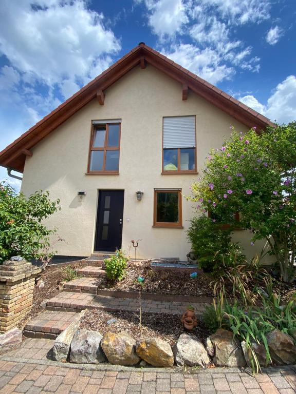 ein weißes Haus mit einem Baum davor in der Unterkunft Ferienhaus am Waldrand Village Holiday home in Bobenheim am Berg