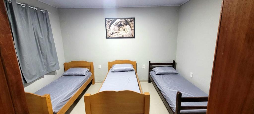 une chambre avec deux lits et un tableau au mur dans l'établissement Aliança da Fé, à Cachoeira Paulista