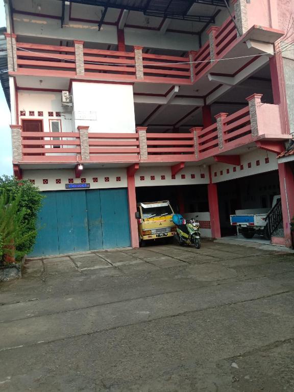 a building with a car parked in a parking lot at Penginapan ANGLING DARMA in Cidaun