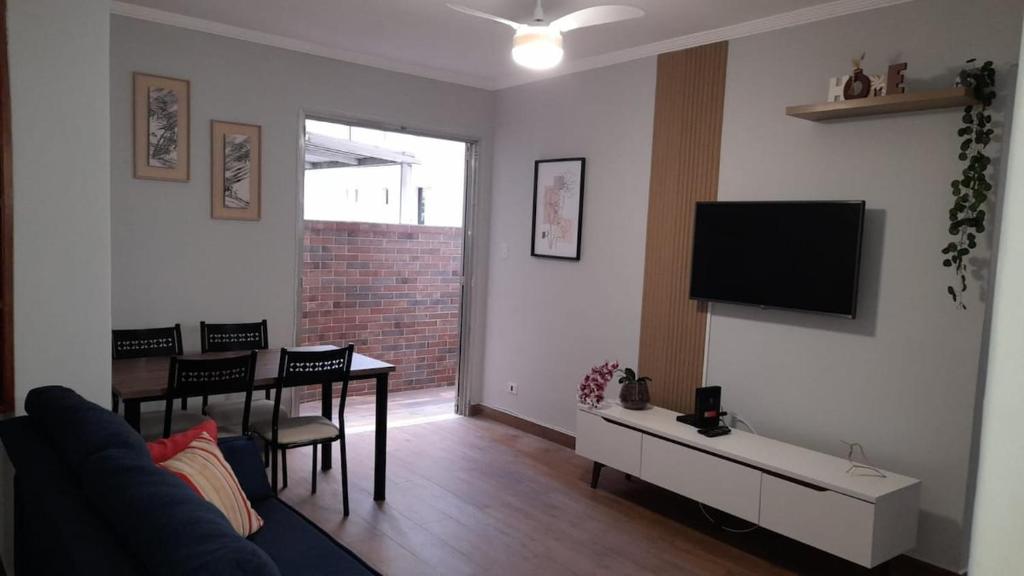 Una sala de estar con un sofá y un televisor en la pared. en Apartamento Frente Praia Embaré - Varanda Aconchegante - Pet Friendly, en Santos