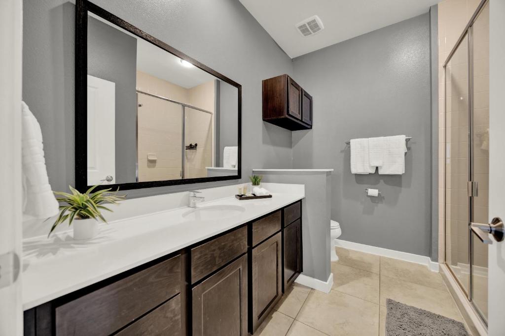 Un baño con lavabo, espejo y ducha. en Beautiful 3 Bedroom Villa with Private Hot Tub, 10 mins to Disney!, en Kissimmee