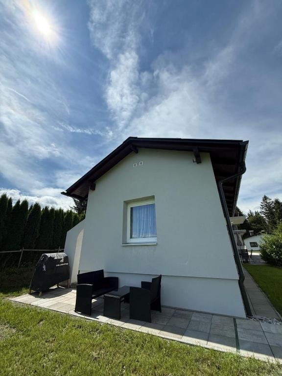 a white house with two chairs and a window at Ferienhaus Rafaela mit Privatstrand in Ledenitzen