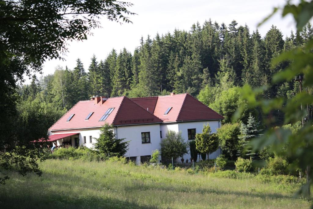 a white house with a red roof in a forest at Dom Supełek in Duszniki Zdrój