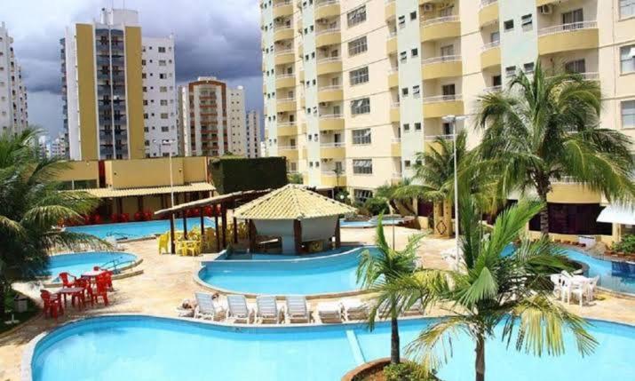 a resort with two pools and chairs and palm trees at Thermas Place Flat in Caldas Novas