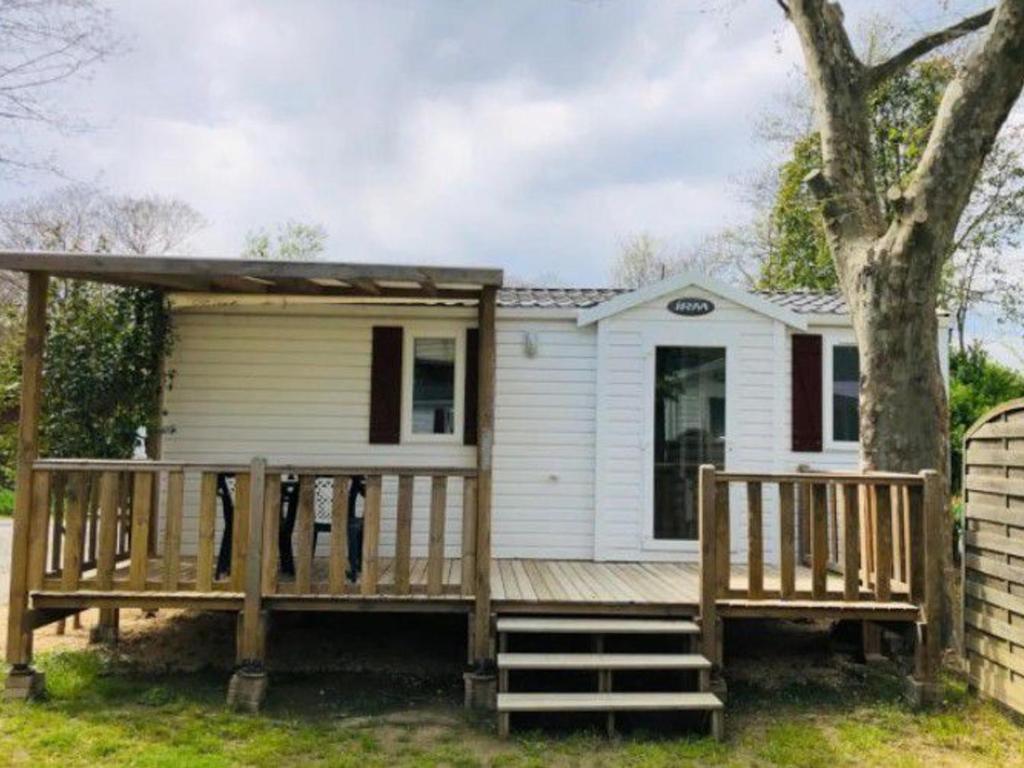 a small white house with a large wooden deck at Mobil-home confortable avec terrasse pour 4 personnes - API-1-52-413 in Massillargues-Attuech