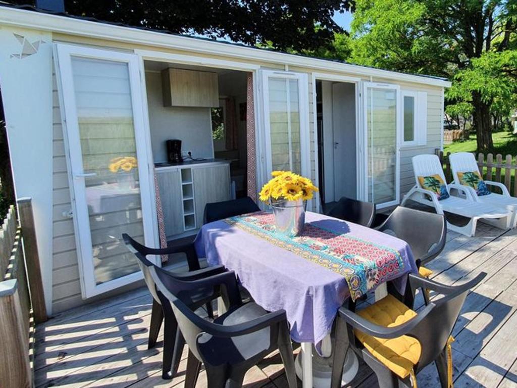 un patio con tavolo e sedie e cucina di Mobil-home 4 pers avec terrasse au camping Les Tournesols - API-1-52-489 a Crissé
