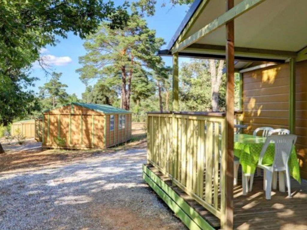 une terrasse avec une table et des chaises dans une maison dans l'établissement Mobil-home 7 pers avec terrasse - API-1-52-737, à Esparron-de-Verdon