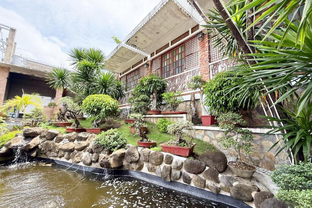 a garden with a pond with potted plants and a building at Casa Lorenzo powered by Cocotel in Daraga