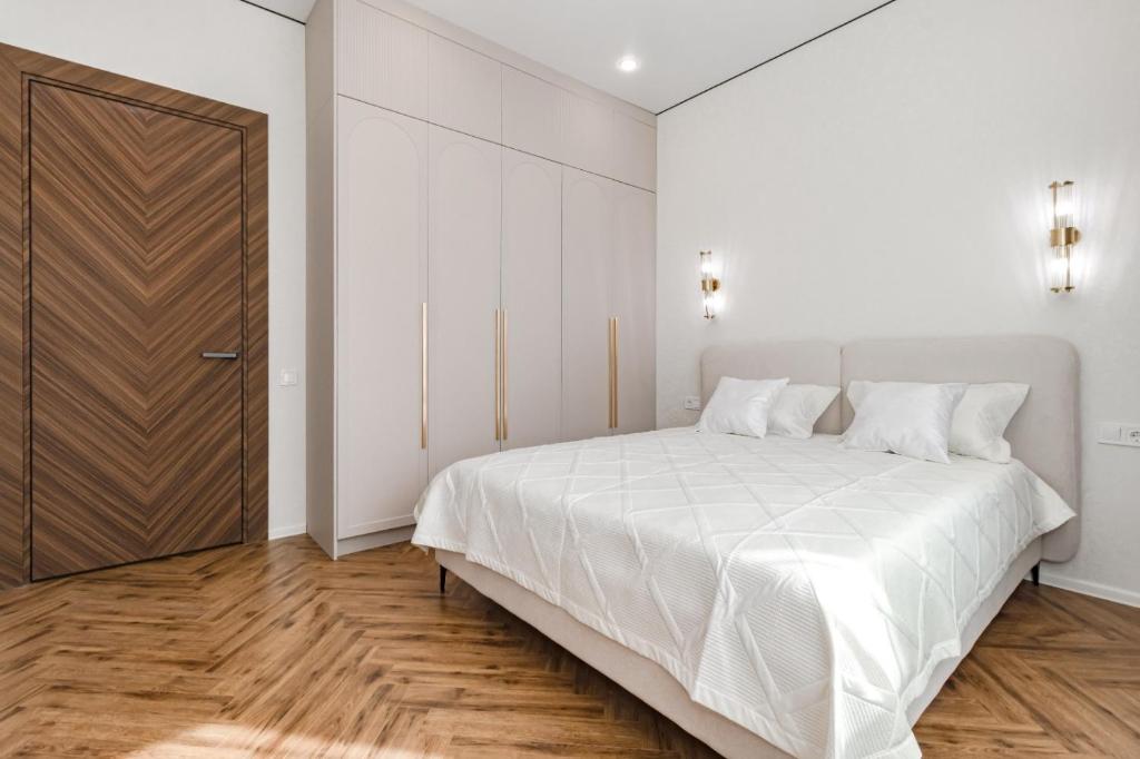 a bedroom with a large white bed and a wooden floor at GreenLine Atmosfera luxe 2 bedroom apartment in Zhezdi