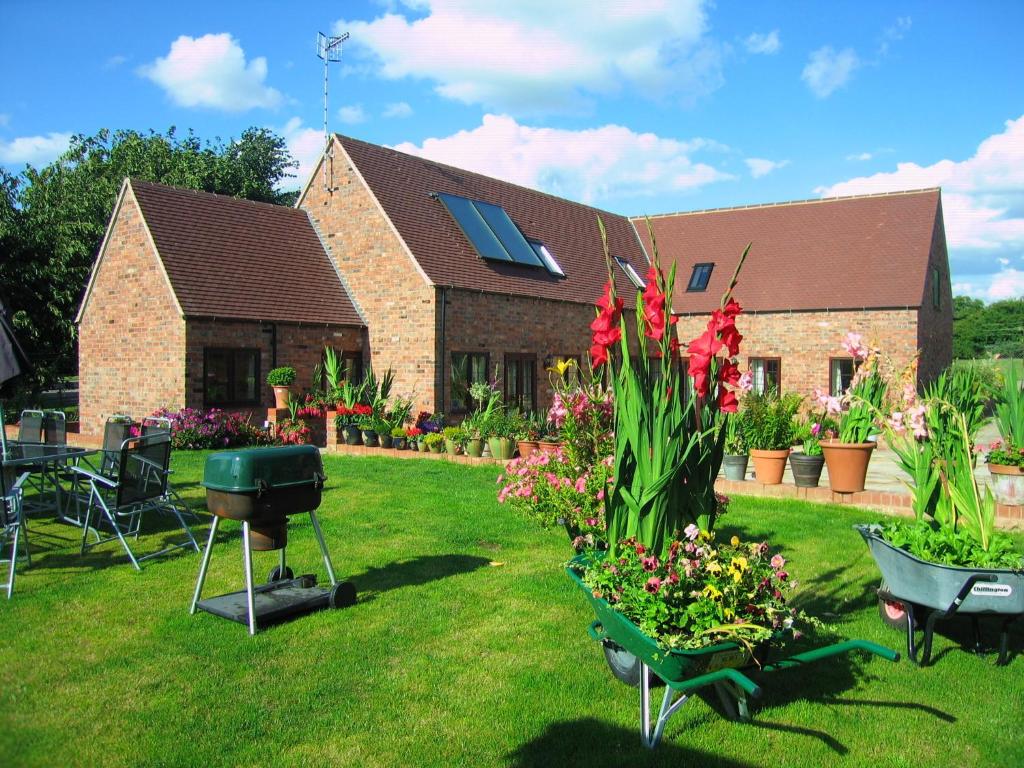 a house with flowers and a grill in the yard at Church Farm Barns in Stratford-upon-Avon