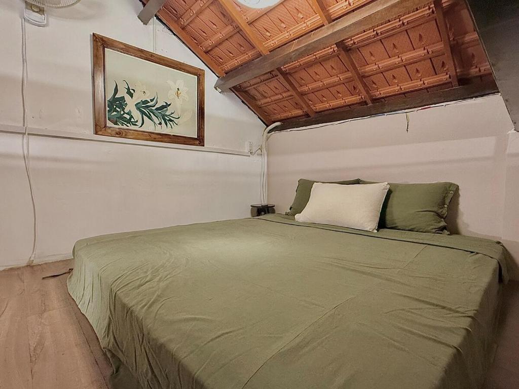a bedroom with a green bed with a picture on the wall at Peaceful Vietnamese - Style House, Yard & Bathtub in Da Nang