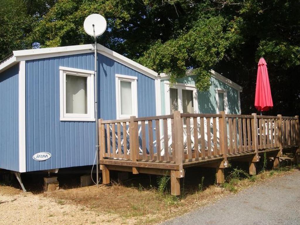 a blue house with a deck and an umbrella at Cabane spacieuse avec terrasse au calme, idéale pour 8 personnes - API-1-52-790 in Saint-Sornin