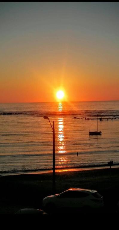 a sunset over the ocean with a boat on the beach at Hospedaje La Tuna in Rocha