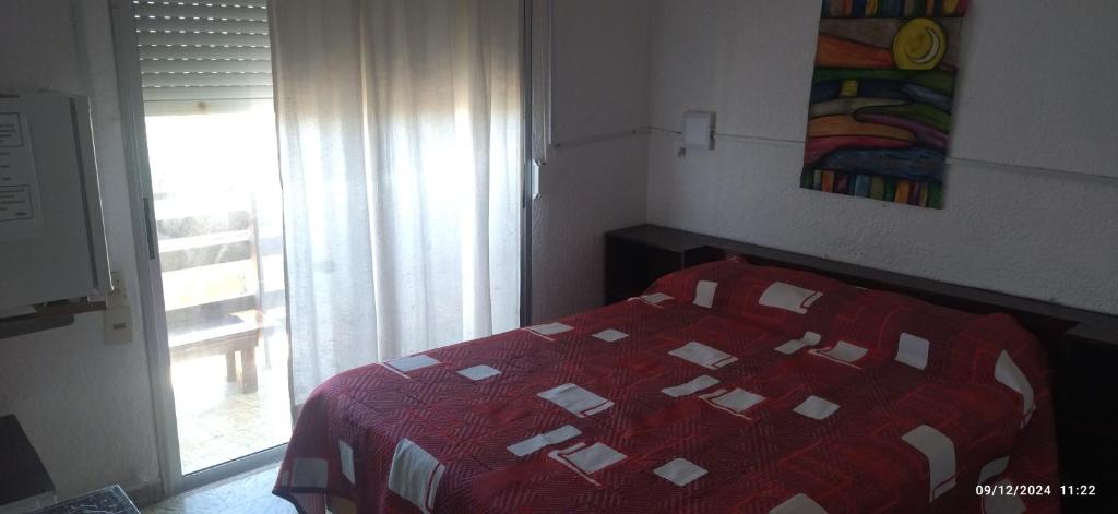 a bedroom with a bed with a red quilt and a window at Hospedaje La Tuna in Rocha