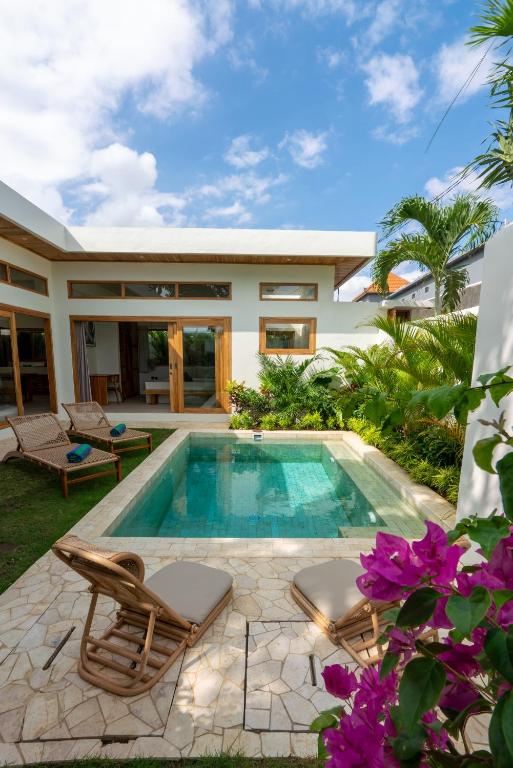 a swimming pool with two chairs and a house at 2Bedrooms Bright&Modern Villa near Balangan Beach! in Jimbaran