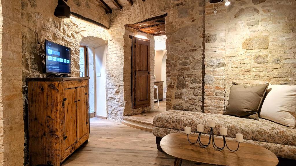 Una sala de estar con un sofá y un televisor en Saxa Suite - Dimore nel Tempo, en Perugia