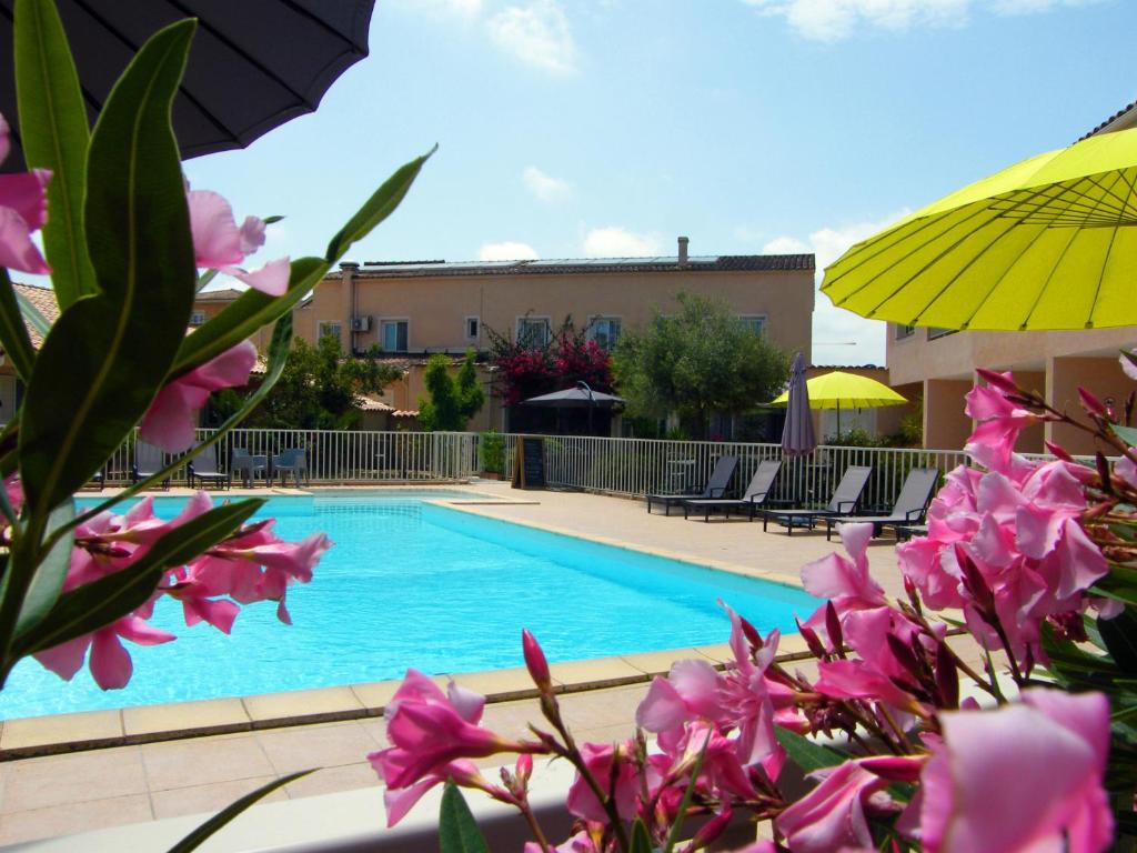 a pool with pink flowers and a yellow umbrella at Hôtel Restaurant L' Empereur in Aléria