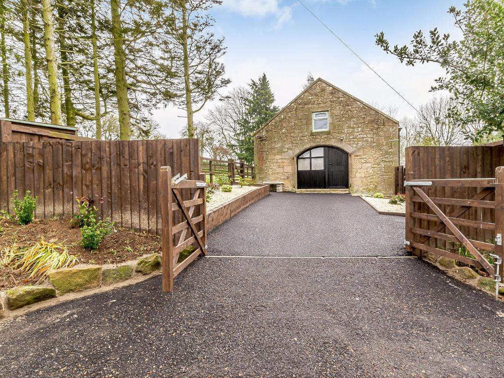 a driveway with a gate and a stone house at Shawdon Hill Coach House in Alnwick