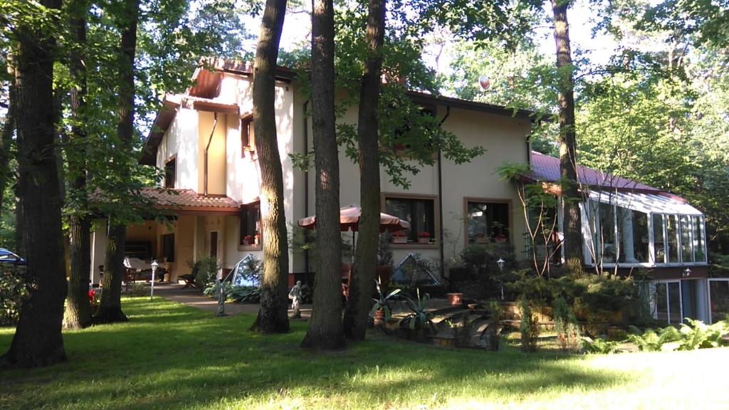 una casa con árboles delante de ella en Villa Podkowa, en Podkowa Leśna