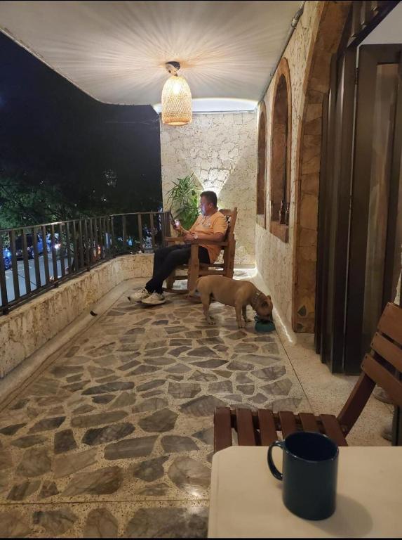 a man sitting in a chair with a dog on a patio at Casa Manila Medellin in Medellín