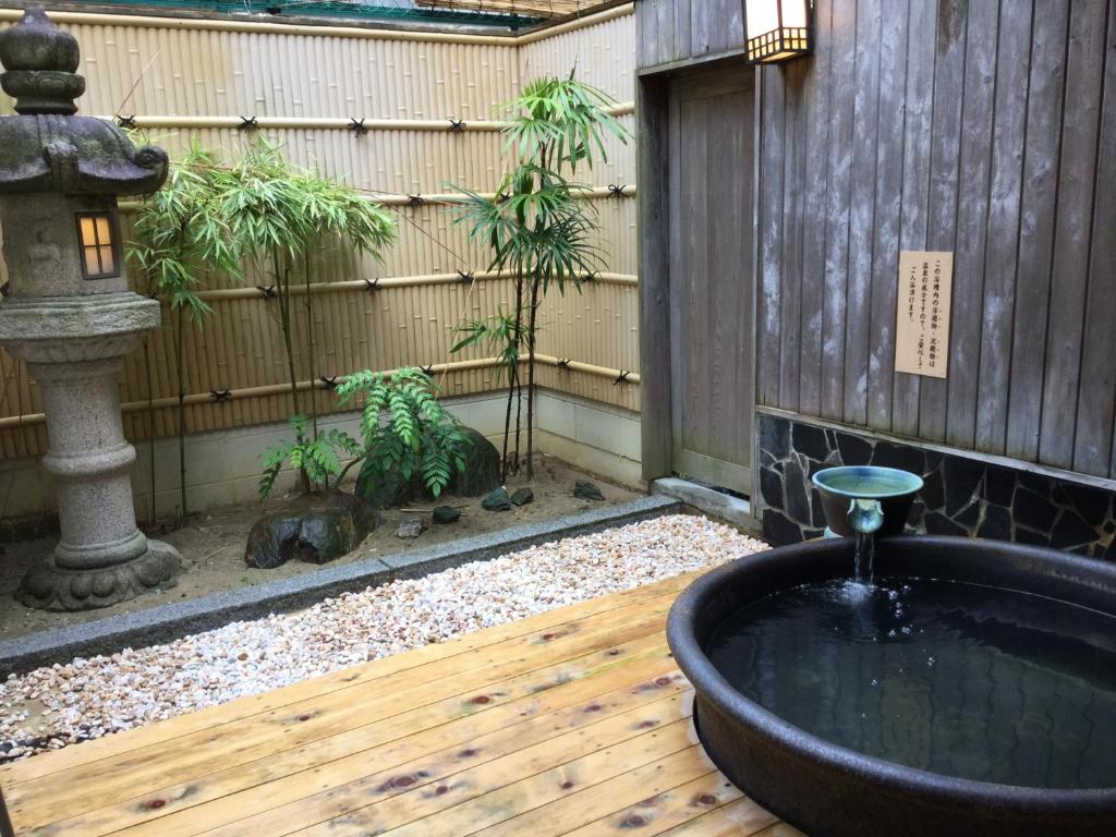 a japanese garden with a bath tub and a fountain at Utsumionsen Ichizu in Minamichita
