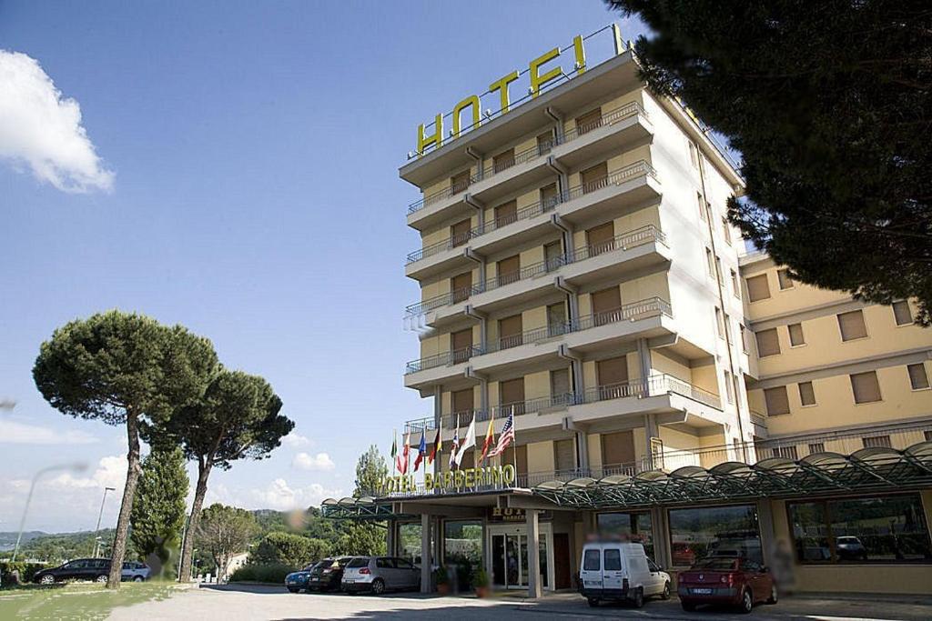 un grand hôtel avec des voitures garées devant lui dans l'établissement Hotel Barberino, à Barberino di Mugello