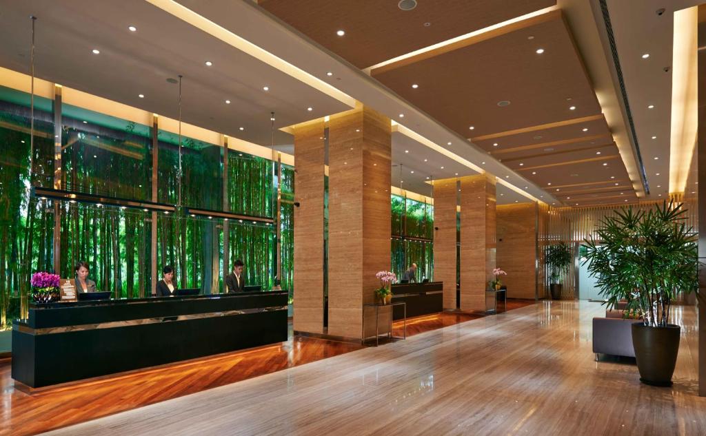 A spacious modern lobby with multiple reception desks and a green-lit feature wall.