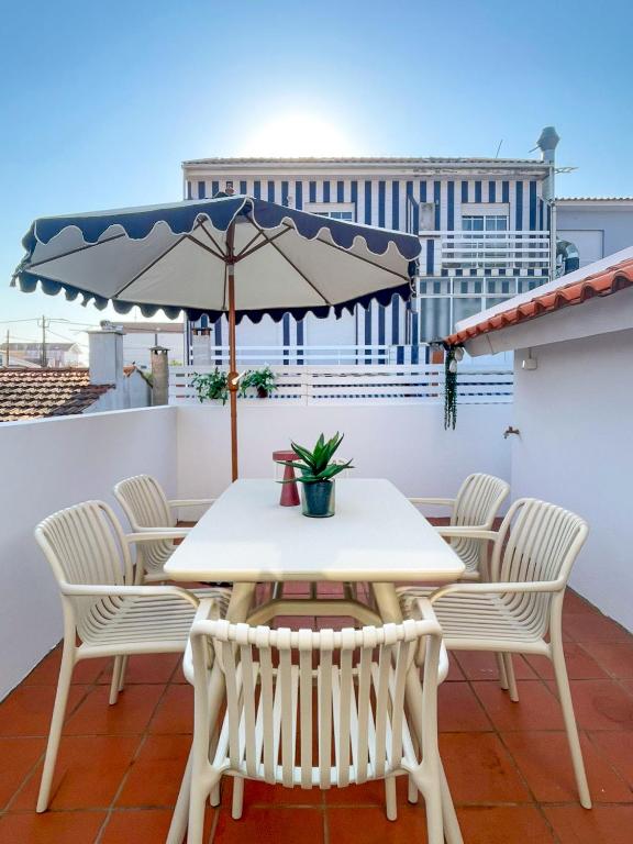 a table and chairs on a balcony with an umbrella at Pijamas House in Gafanha da Encarnação