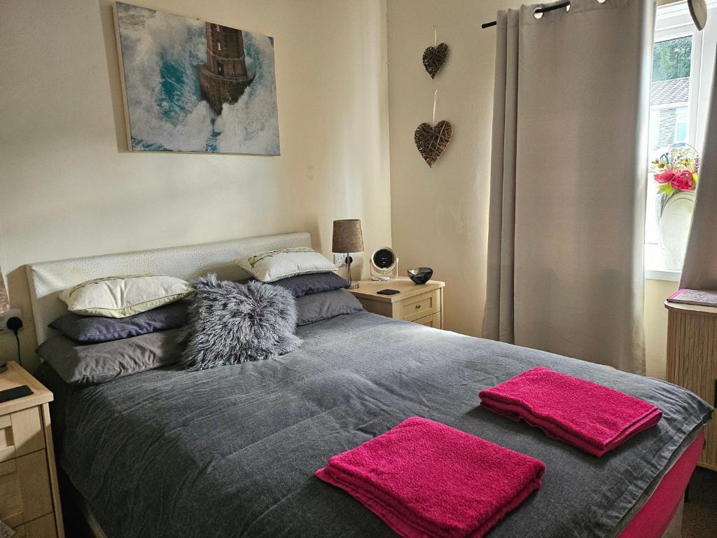 a bedroom with a bed with two pink towels on it at Shalom, in Saundersfoot, near the sea in Saundersfoot