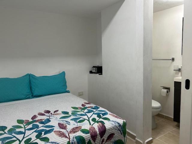a bedroom with a bed and a bathroom with a toilet at Pequeño Alojamiento in Cancún