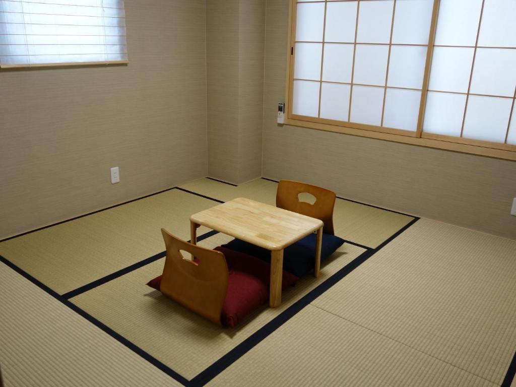 a room with a table and chairs on the floor at Guesthouse WIND VILLA Kyoto in Kyoto