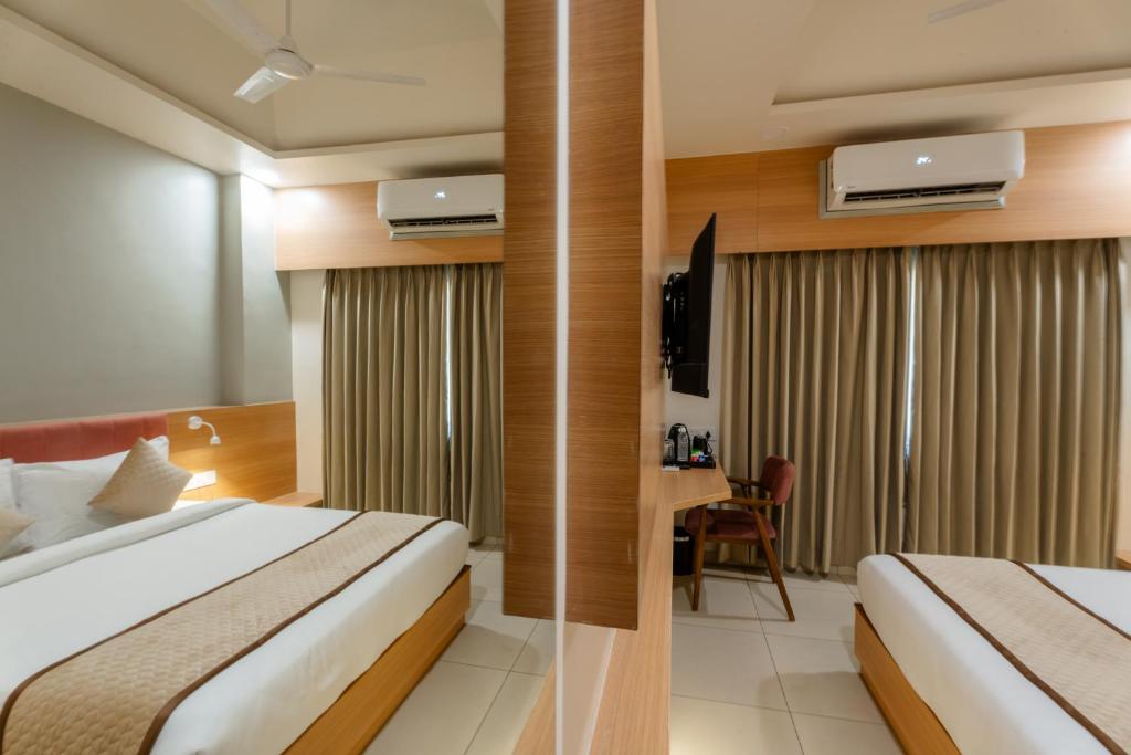 een hotelkamer met twee bedden en een bureau bij Prarambh By Siara in Nadiād