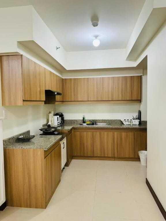 a kitchen with wooden cabinets and a counter top at Vtan Condo in Manila
