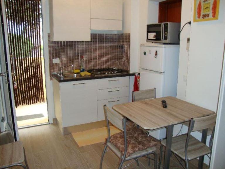 a kitchen with a wooden table and a refrigerator at Bilocali e Mono al mare in Senigallia