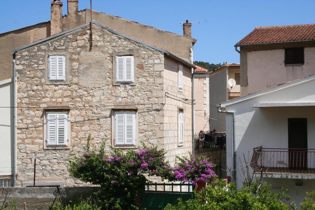 an old stone building with white windows and purple flowers at Holiday Home Isabella in Vis