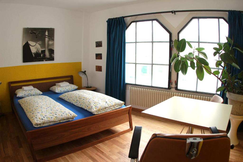 1 dormitorio con 2 camas, mesa y ventanas en Basel Backpack, en Basilea