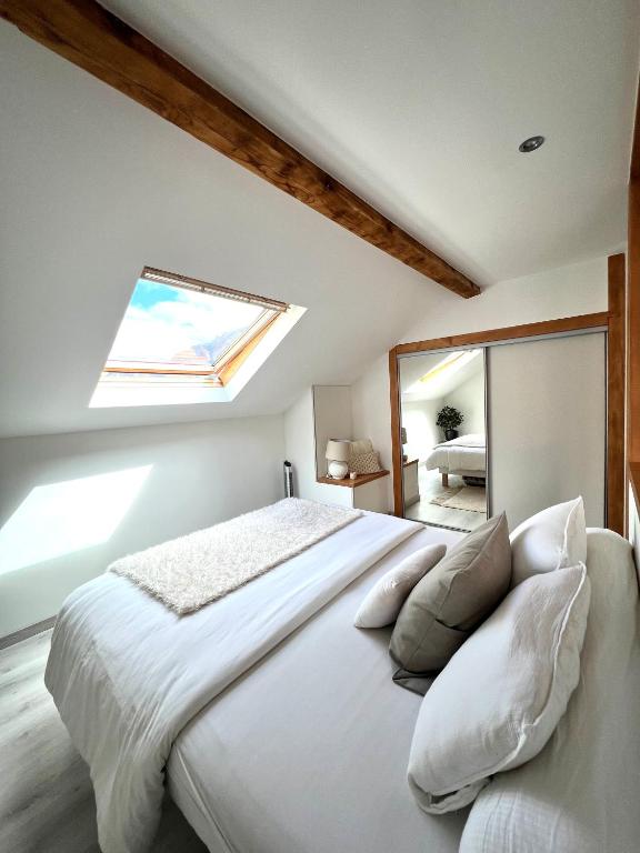 a bedroom with a large white bed with a skylight at Duplex MontBlanc - Suite, Centre & Parking by AlpenlySallanches in Sallanches